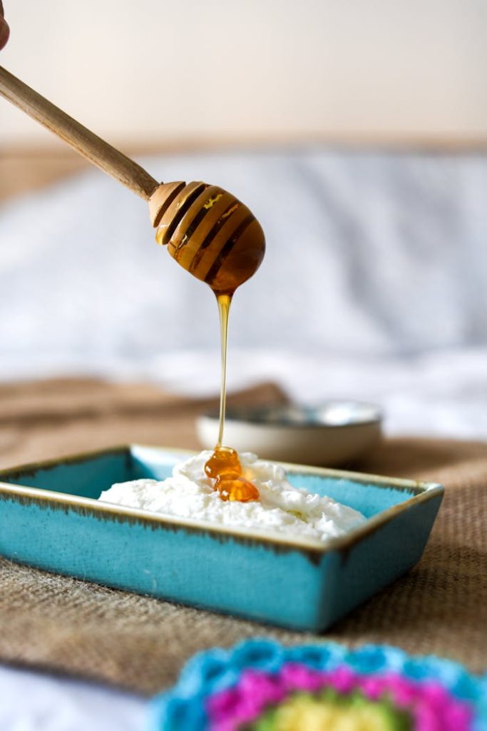 Close-up of honey drizzling over fresh ricotta in a blue dish. Perfect for food enthusiasts.