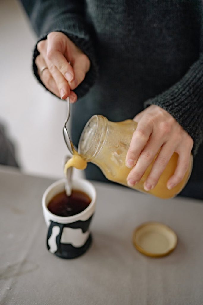 A person pours honey into a teacup, creating a warm, cozy atmosphere.